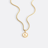 Necklace with a letter on a mother-of-pearl disk on a braided chain